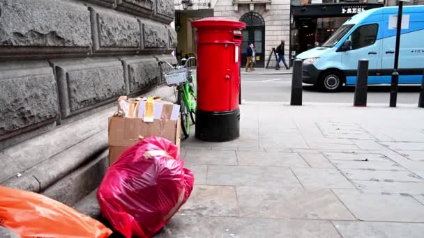 LONDON - 04. FEBRUAR 2020: Ein zwischen einer Mauer und einem traditionellen roten britischen Postkasten abgestelltes Leihfahrrad mit ausrangiertem Müll im Vordergrund