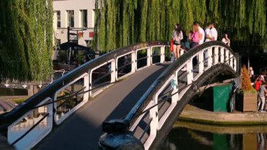 Londra - 14 Eylül 2020: PPE maskeli Asyalı bir kadın Camden Lock kanalı üzerindeki köprüden batan güneşin sıcacık ışığında geçiyor..