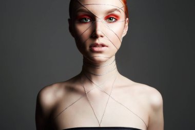 Moda güzellik makyaj kız portakal göz farı ile portresi. Yüz ve vücut üzerinde makyaj ve gümüş iplik ile güzel genç kadın