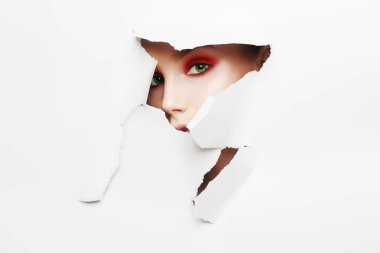 Yüz kağıt bir deliğe parlak bir makyaj ile güzel bir genç kız. Güzellik, moda, kişisel bakım, kozmetik, makyaj, sağlık, güzellik salonları, makyaj sanatçısı