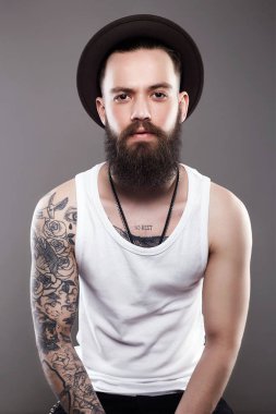 Dövmeli sakallı yakışıklı şapkalı. Acımasız hipster çocuk dövme ile