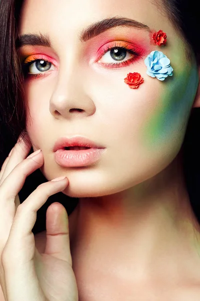 顔に花を持つ美しい少女 美容のカラフルなメイクアップ女性 — ストック写真