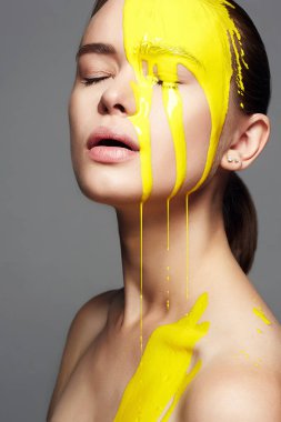 Genç kadın sarı boya. bir güzel yüz ve vücut bölgesine akan sıvı boya. Kız boya renk portresi