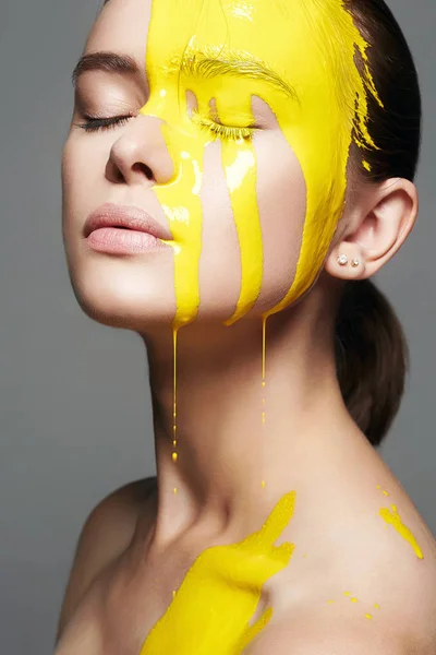 黄色の塗料で 若い女性 美しい顔と体を流れる液体の塗料 ペイントで女の子の色の肖像 — ストック写真