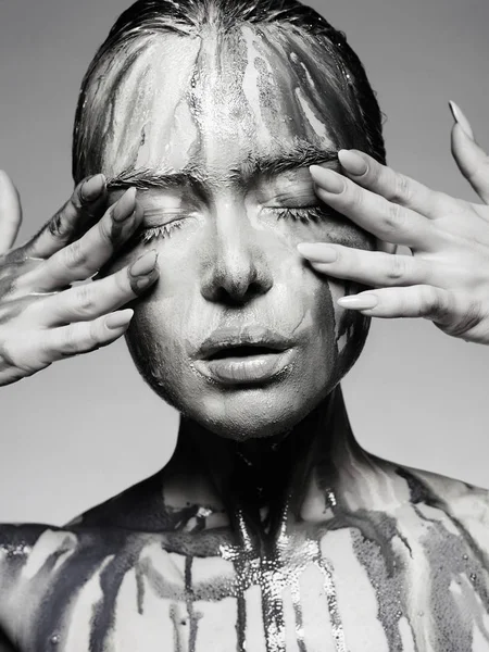 Young woman with Dirty Face. liquid paint flowing over a beautiful face and Body. Girl in Paint