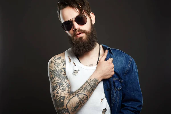 Modne Przystojny Mężczyzna Tatuażem Okulary Przeciwsłoneczne Hipster Brodaty Chłopiec Dżinsy — Zdjęcie stockowe
