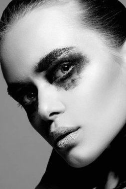 Güzel genç kadın kirli boya yüzü ile siyah beyaz portre. bir yüz ve vücut üzerinde boya. Kız siyah boya