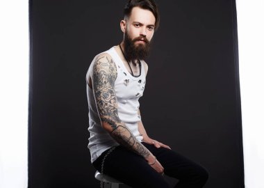 sakallı yakışıklı adam. Vintage yırtık kıvranıp acımasız sakallı hippi. Şık saç kesimi ve dövme bir çocuk