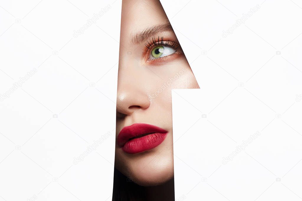 young beautiful woman with red lips makeup into the hole of white paper. make-up artist concept. number one