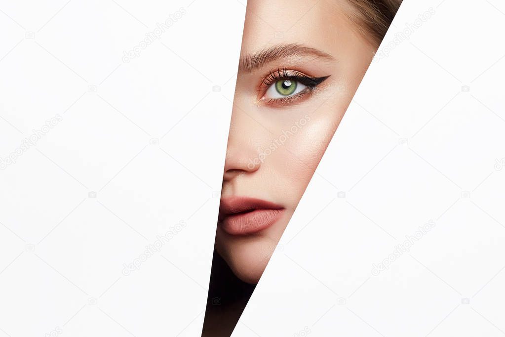 young beautiful woman with makeup into paper hole. make-up artist concept. arrows on the eyes.