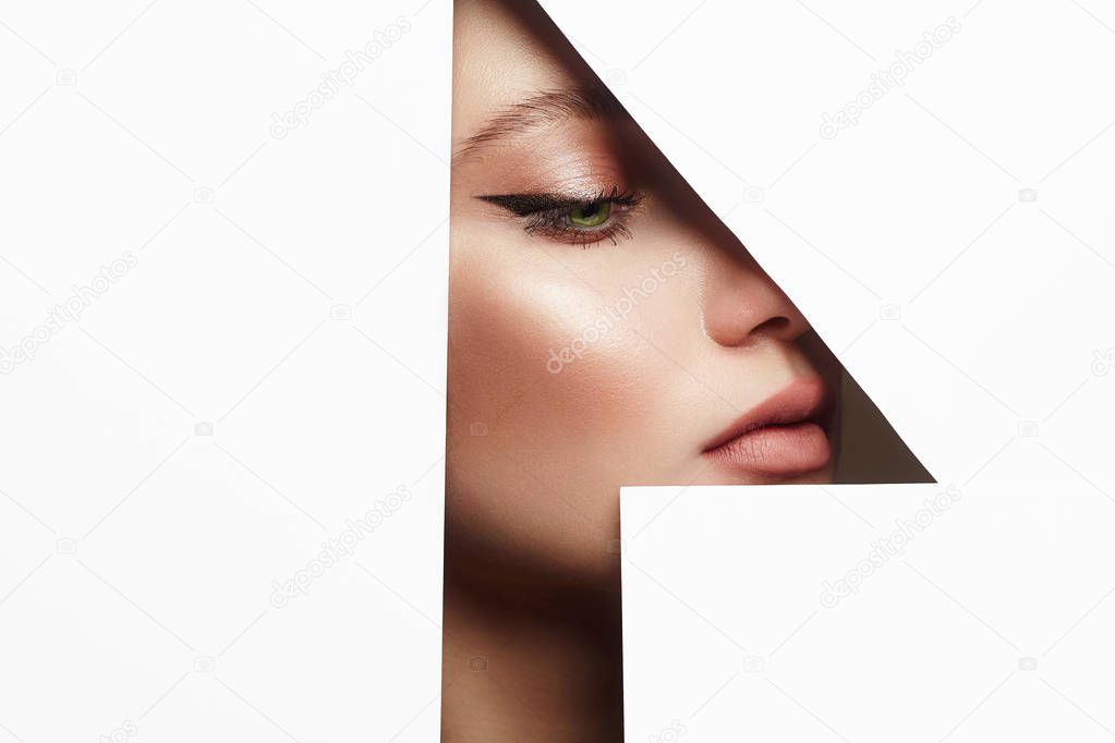young beautiful woman with makeup into paper hole. make-up artist concept. arrows on the eyes. number one