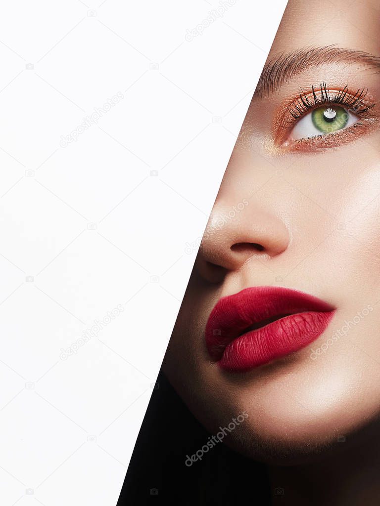 beautiful woman with a makeup, into the hole of white paper. make-up artist concept. beauty girl with beautiful bright green eyes and red Lips