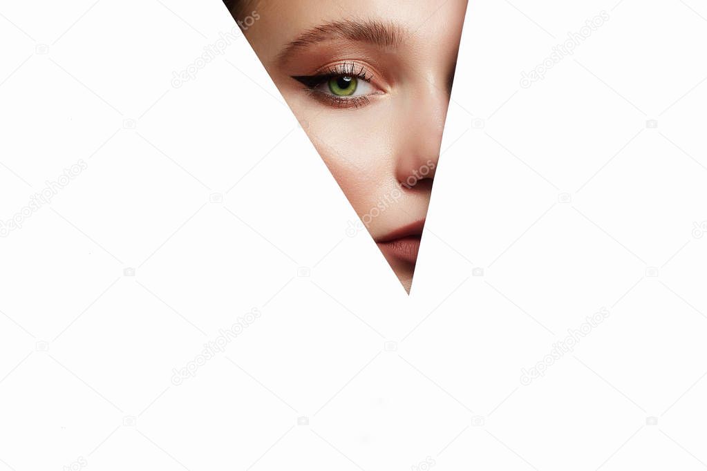 young beautiful woman with makeup into paper hole. make-up artist concept. arrows on the eyes.