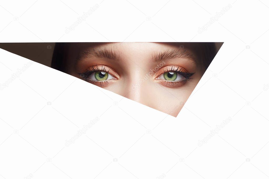 young beautiful woman with makeup into paper hole. make-up artist concept. arrows on the eyes. number one