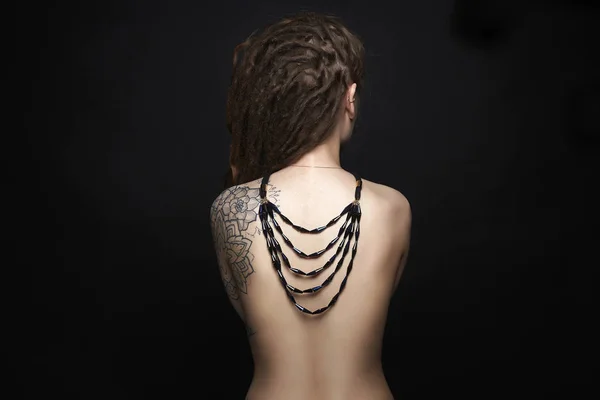 Menina nua com tatuagem e colar em suas costas — Fotografia de Stock