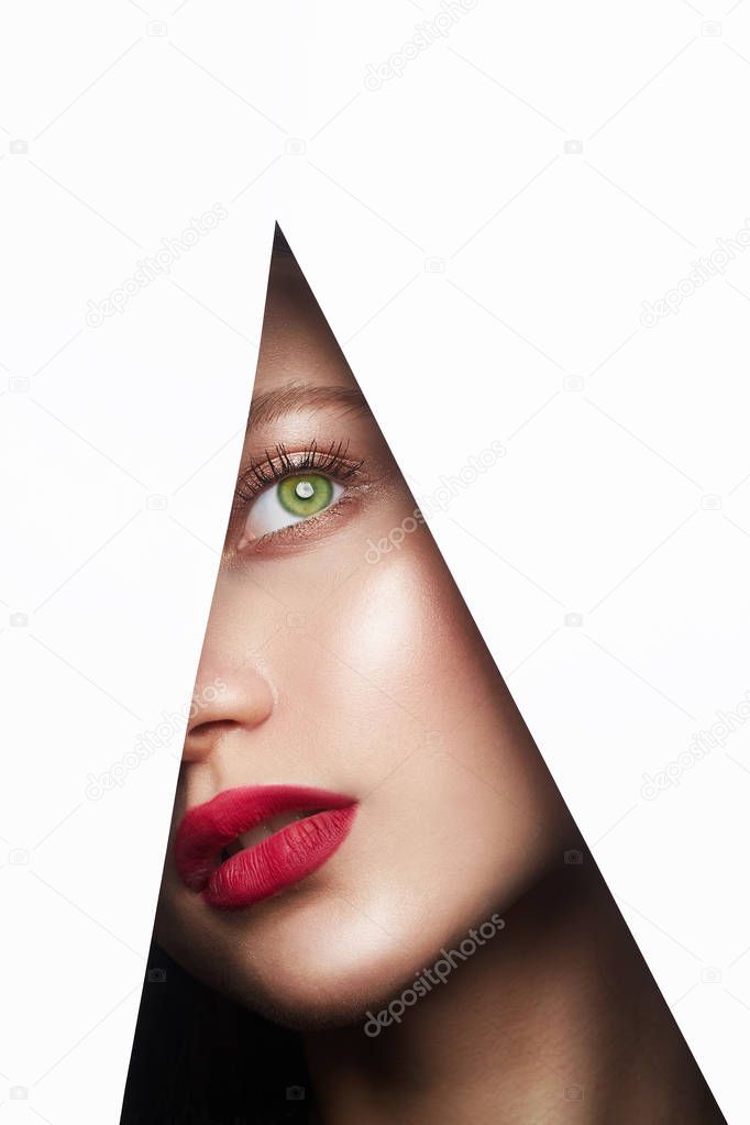 young beautiful woman. female face with makeup into paper hole