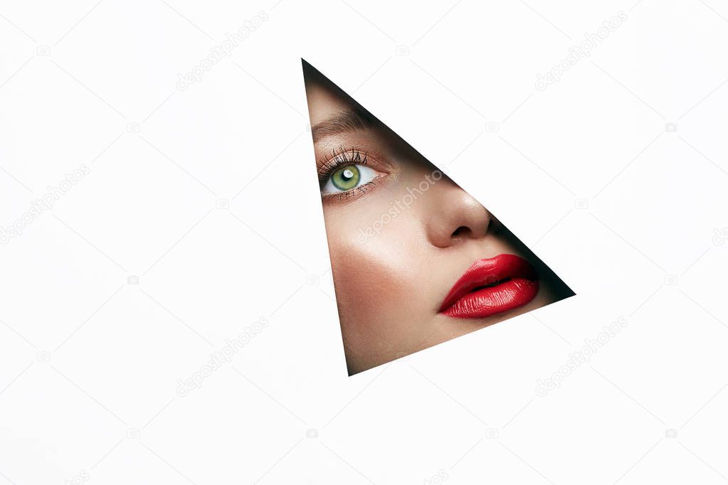 young beautiful woman. female face with makeup into paper hole