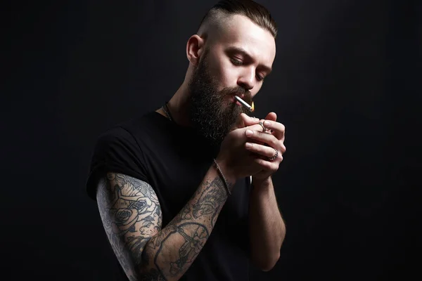 handsome Brutal bearded smoking man. Hipster tattoed boy