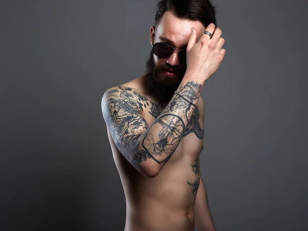 Hombre barbudo en gafas de sol, cuerpo masculino joven tatuado desnudo — Foto de Stock