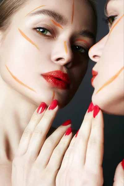 Espejo. Mujer joven con maquillaje de pintura naranja — Foto de Stock