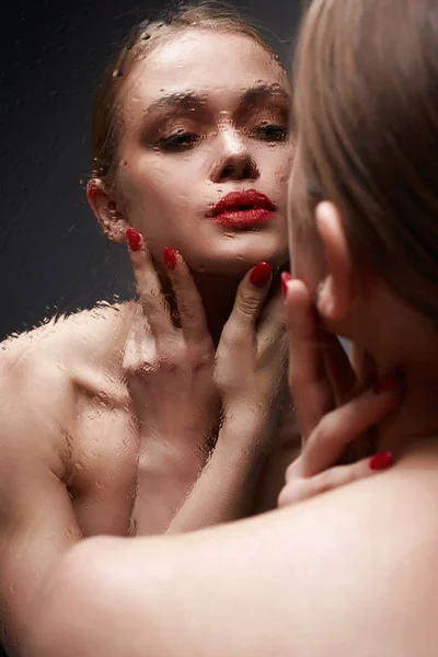 Bela jovem mulher olhando no molhado espelho — Fotografia de Stock