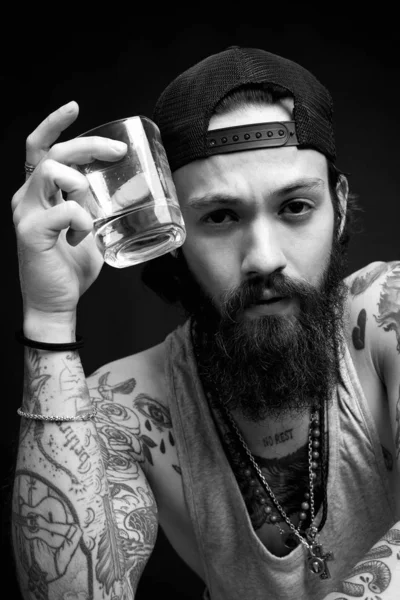 handsome bearded man with tattoo enjoying whiskey