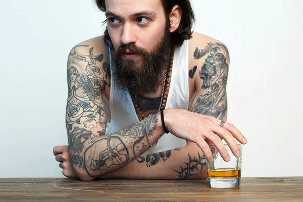 あごひげと入れ墨を持つ男。ウイスキーのグラスを持つ男 — ストック写真