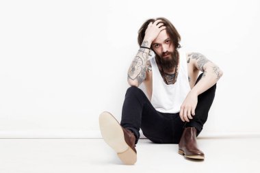 Stüdyoda oturan sakallı çocuk.