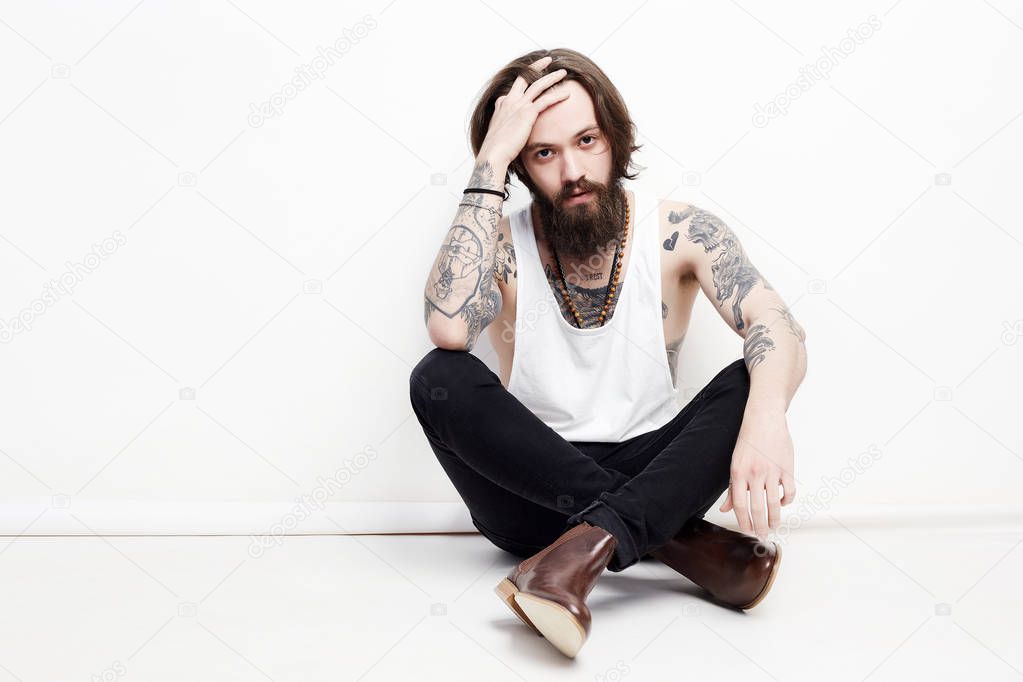 bearded boy with tattoo sitting in studio