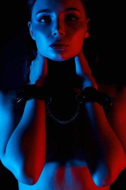 Kelepçeli bir kız. Renkli ışıklar içinde güzel bir genç kadın. Sanat tasarımı, parlak vücutlu renkli bir kız. ellerim bağlı