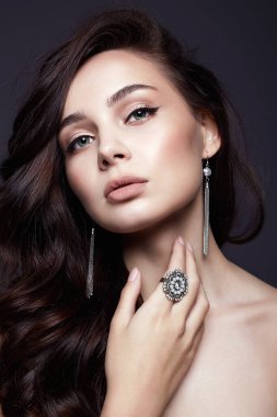 Sağlıklı kıvırcık saçları ve mücevherleri olan güzel bir kadın. Seksi model kız. moda güzellik portresi