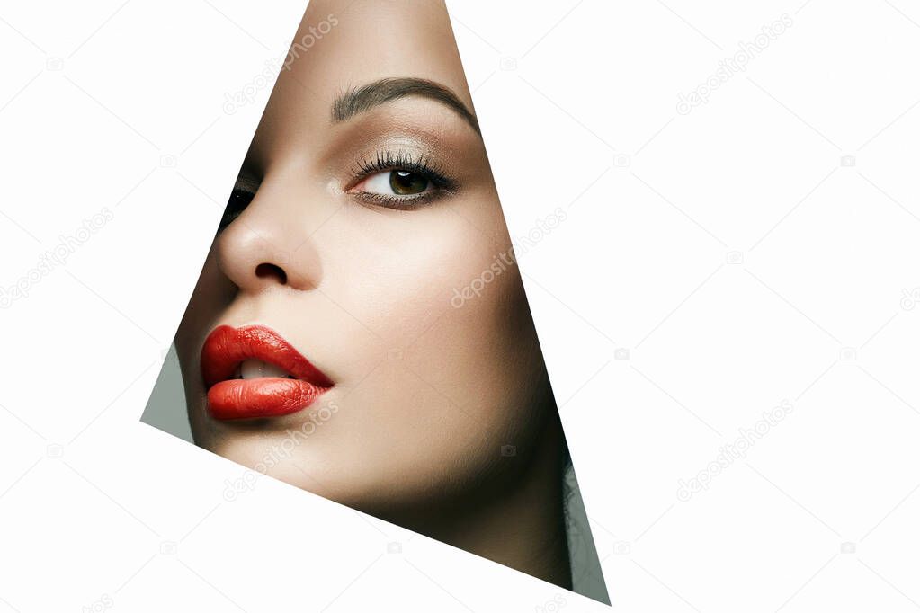 beautiful woman. female face with makeup into paper hole. make-up artist concept. arrows on the eyes.