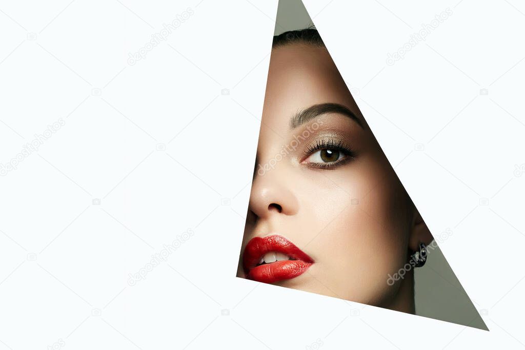 beautiful woman. female face with makeup into paper hole. make-up artist concept