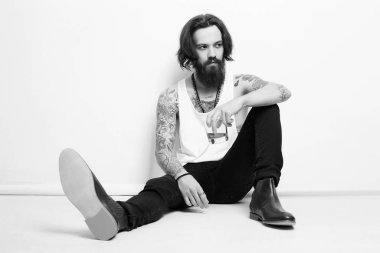 Sakallı ve dövmeli sarhoş bir adam. Elinde bir bardak viskiyle yerde oturan adam. Sakallı hippi çocuk portresi