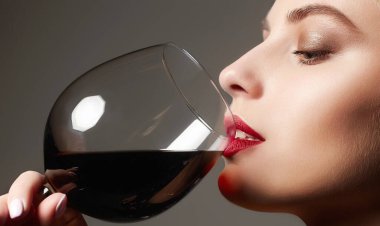 Güzel, mutlu bir kadın şarap içiyor. İçki içen kızın yakın plan fotoğrafı.