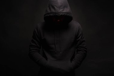 Siyah Başlıklı Adam karanlık stüdyoda poz veriyor. Kapüşonlu kazaklı bir çocuk. Erkek portresi