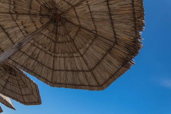 Hasır bir şemsiye ve yaz göğün altında yalan. bakış açısı