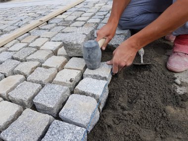 İnşaat işçisi bir sokakta bulunan eski bir şehir merkezi tadilatı için bir kaldırım düzenlenmesi
