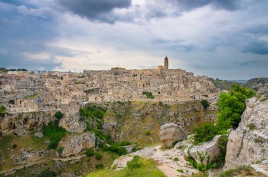 Matera panoramik Sasso Caveoso eski antik şehrin tarihi merkezinin Sassi di Matera dramatik gökyüzü ile mağara taş evleriyle görüntülemek Murgia Timone, Unesco miras, Basilicata, Güney İtalya