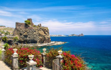 Norman eski ortaçağ Şatosu Aci Castello Akdeniz 'in suları yakınında kaya duvarları ve kırmızı çiçekli çitler, Catania, Sicilya, Güney İtalya