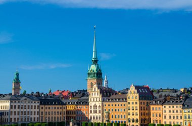 Kornhamnstorg liman Meydanı eski tarihi şehir çeyreğinde Gamla Stan mavi gökyüzü, Stockholm, İsveç ile çatılar ve renkli duvarları ve kuleler Lutheran Alman Kilisesi ile geleneksel yapılar