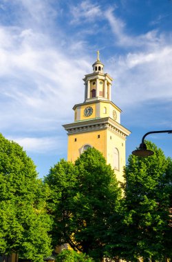 Çan Kulesi ve Protestan Santa Maria Magdalena Kilisesi kyrka yeşil Sodermalm adada saatinde yaprakları ağaçların çevresinde ve mavi gökyüzü beyaz bulutlar arka plan ile Stockholm, İsveç