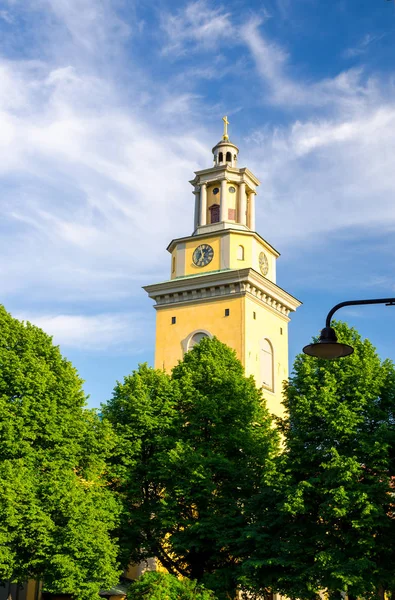 Çan Kulesi ve Protestan Santa Maria Magdalena Kilisesi kyrka yeşil Sodermalm adada saatinde yaprakları ağaçların çevresinde ve mavi gökyüzü beyaz bulutlar arka plan ile Stockholm, İsveç