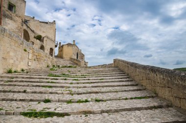 Taş merdiven yakınındaki tarihi merkezinde şehrin antik kenti Sassi di Matera, Unesco, Basilicata, Güney İtalya Sasso Caveoso bulutlu gökyüzü arka plan ile eski binalar kadar lider arasında çim ile