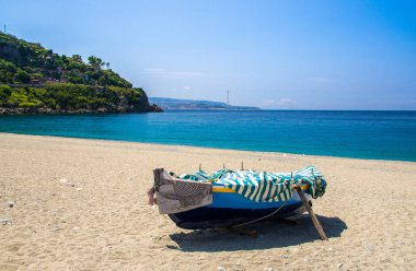 Tiren Denizi kumlu plaj sahil kıyısında güzel sahil kasaba köyü Scilla yeşil tepe, Sicilia Adası ve mavi gökyüzü arka plan, Calabria, Güney İtalya ile renkli balıkçı teknesi