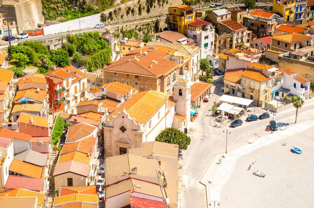 Top view of orange tiled roofs of colorful traditional typical italian houses, church and sandy beach in beautiful seaside town village Scilla, Calabria, Southern Italy