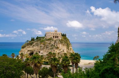 Manastırın kutsal kilise Santa Maria dell Isola Tiren Denizi ve yeşil palmiye ağaçları, mavi gökyüzü beyaz bulutlarda güneşli bir gün, Tropea, Vibo Valentia, Calabria, Güney İtalya ile kaya üzerine