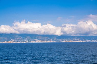 Messina Boğazı bağlı Akdeniz ve Tiren Denizi ve Sicilia ada mavi gökyüzü ve bulutlar beyaz arka plan ile promenade quay waterfront Reggio di Calabria, Güney İtalya görünümünden