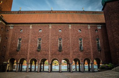 Avlu içinde Stockholm City Hall Lake Malaren görünümü ile kemer, tuğla duvarlar, Belediye Meclisi ve Nobel Ödülü (Stadshuset) bina çatı, mavi gökyüzü, İsveç ile insanlar yürüyen döşenir