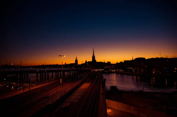 斯德哥尔摩城市景观天际线的剪影与里德郝尔蒙教堂尖顶 市政厅 Stadshuset 大桥美兰湖在老城区日落 黄昏和紫色橙色天空 — 图库照片